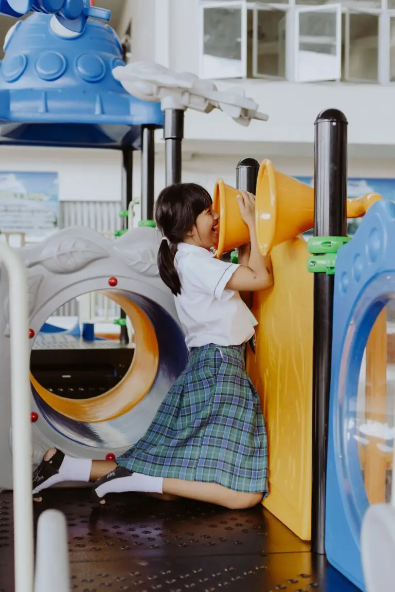 Young girl in school uniform having fun in a colorful indoor playground.