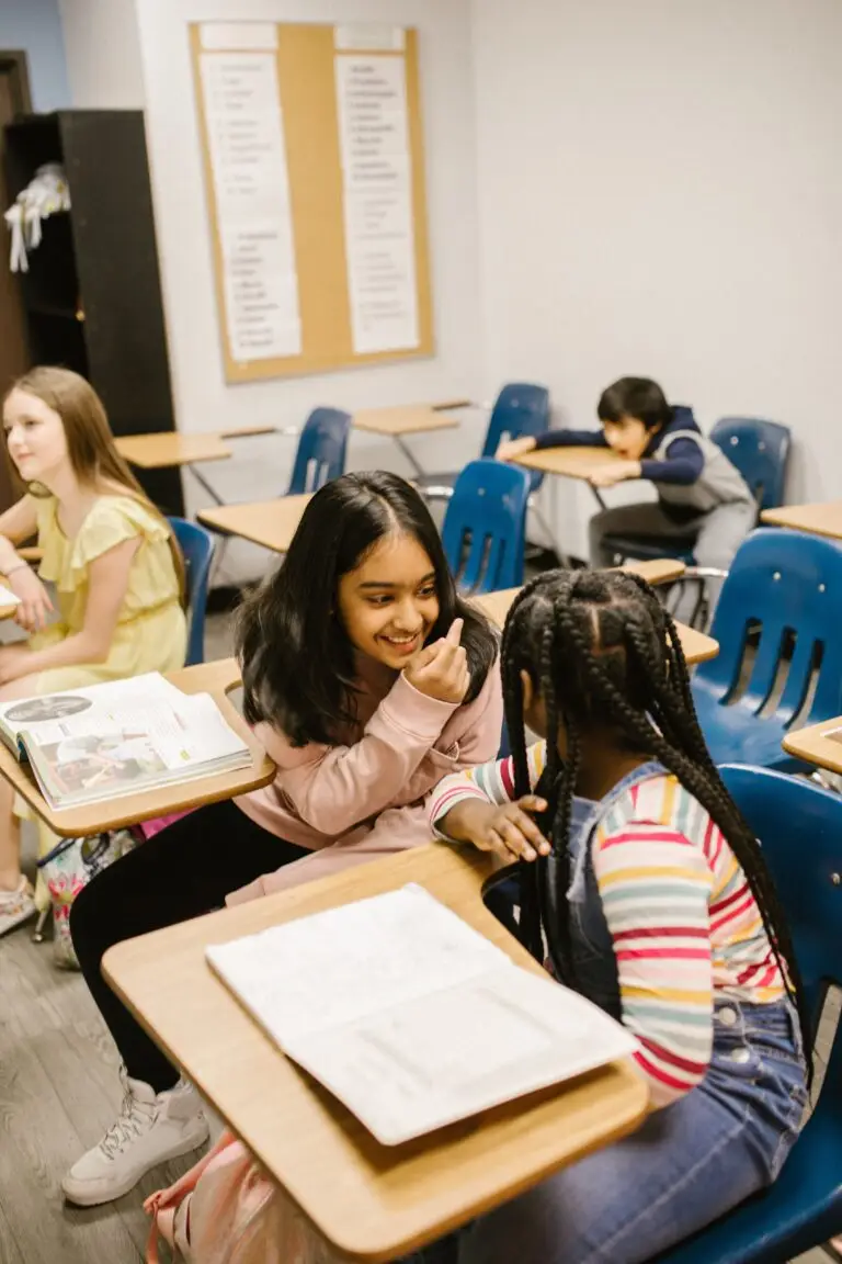 Home A diverse group of students engaging in conversation inside a classroom setting.